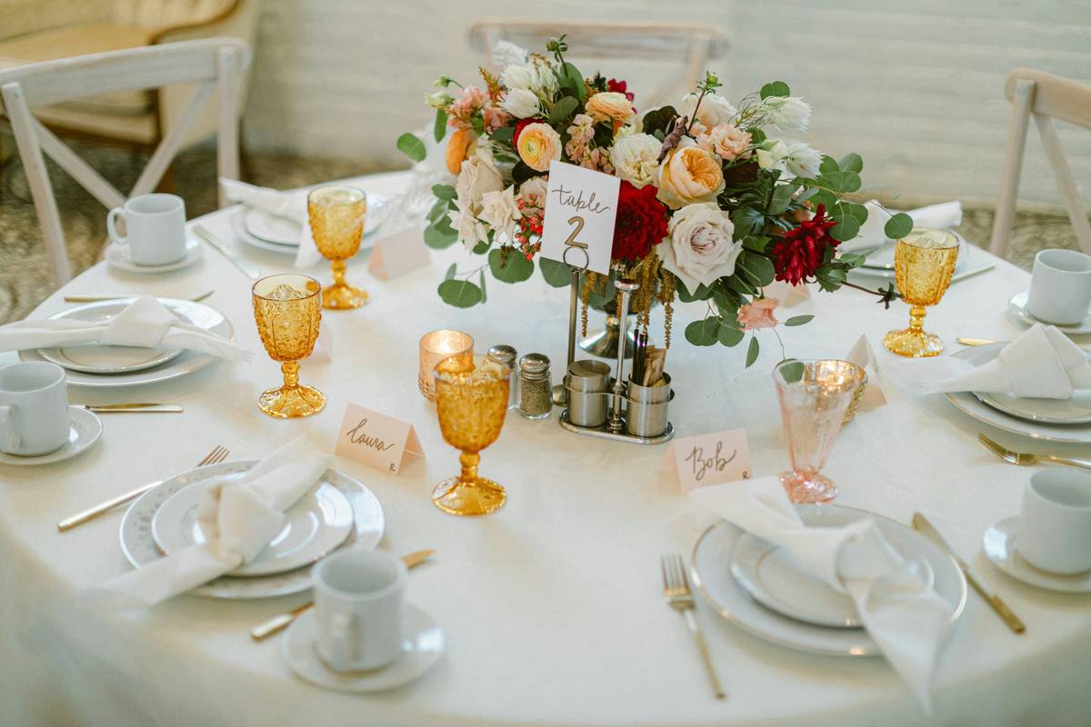 Elegant home decor centerpieces on dining table featuring vintage brass candlesticks and olive branches